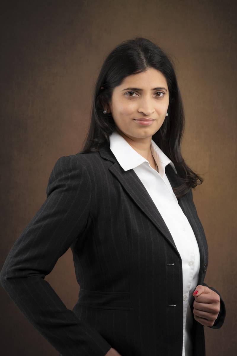 woman in a black business suit with black straight hair below her shoulders