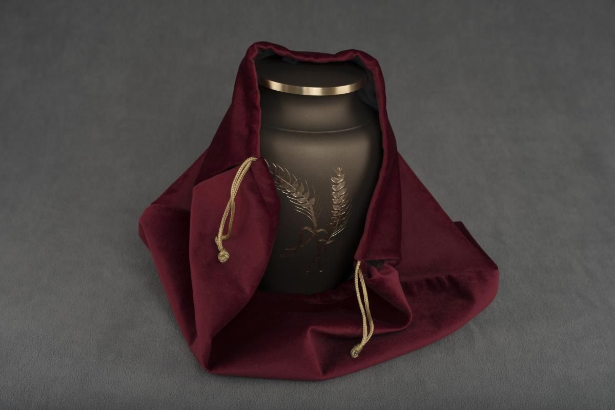 Black ash urn with gold details wrapped in a burgundy velvet cover