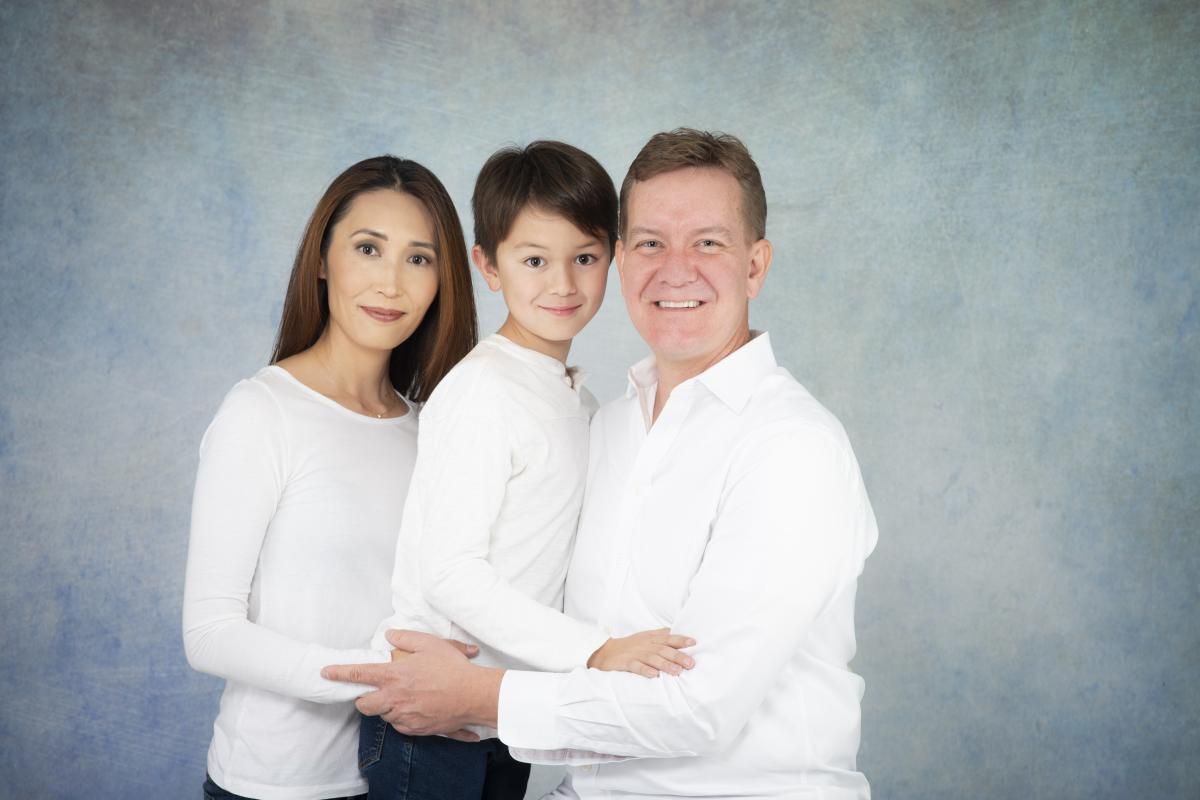 young family in bright clothes embracing posing for a family portrait